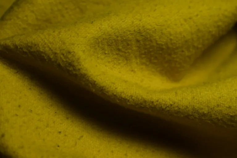 Close-up of textured yellow fabric with folds — illustrative material image